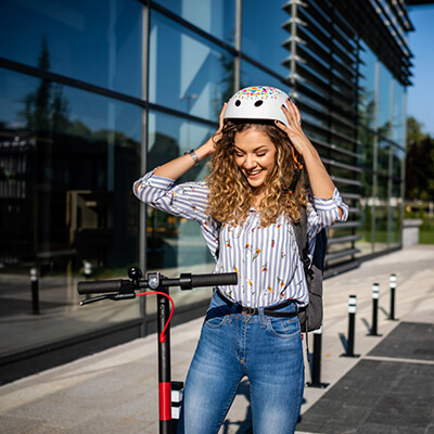 Femme avec casque sur trottinette électrique assurée AGPM